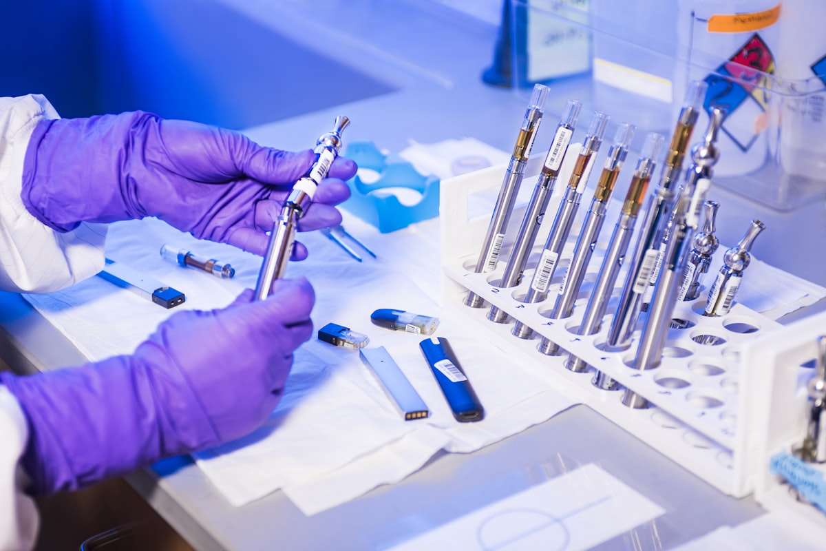 Gloved hands handling a rack of sealed sample ampoules